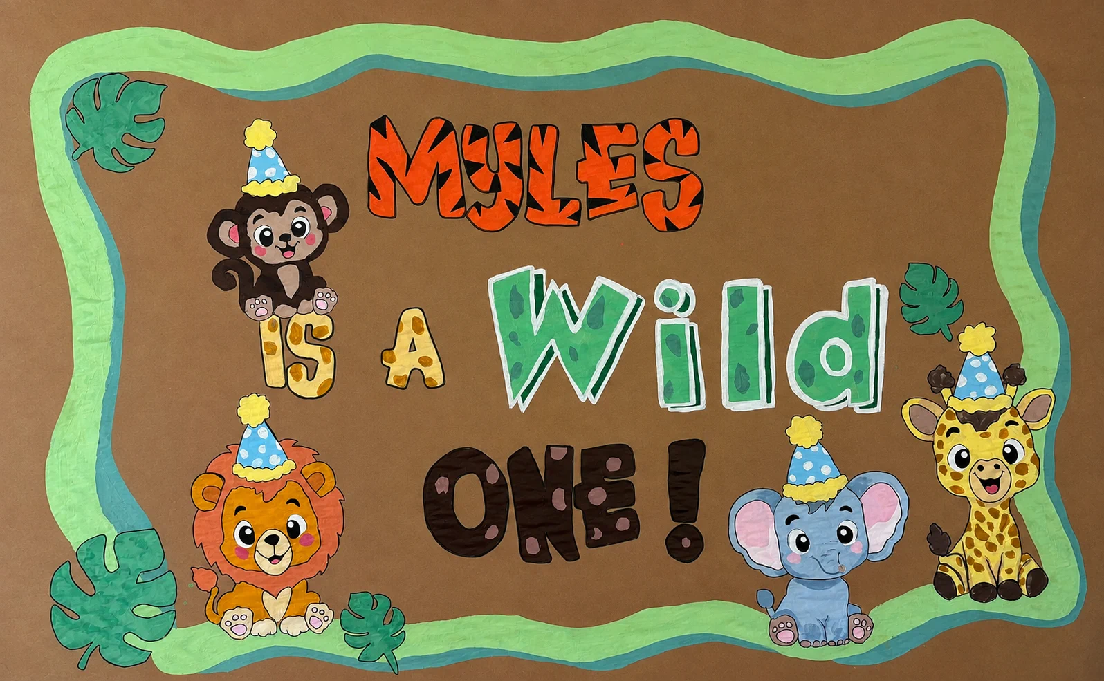 Hand-painted jungle first birthday banner reading Myles Is a Wild One, decorated with a monkey, lion, elephant, giraffe, and tropical leaves